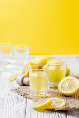 Alcoholic drink, Italian liqueur limoncello in wine-glasses with lemons on a wooden background