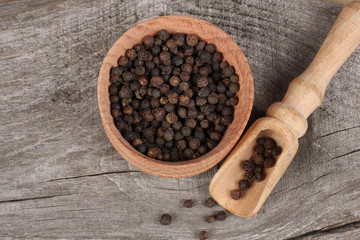 black pepper. peppercorns in wooden bowl on wooden background with copy space. top view