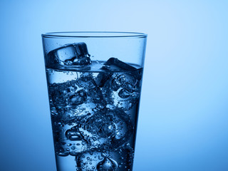 isolated glass of water with ice cubes on a light blue background