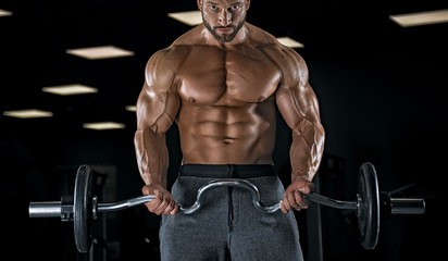 Naklejka na ściany i meble Adult guy bodybuilder posing in gym