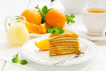 Homemade honey cake with orange cream on a white plate.