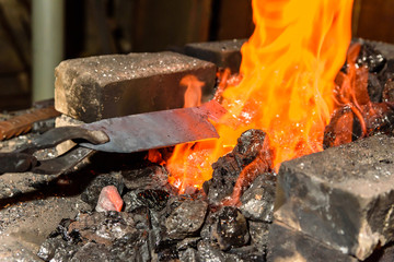Warming up the metal in heat. The forge.
