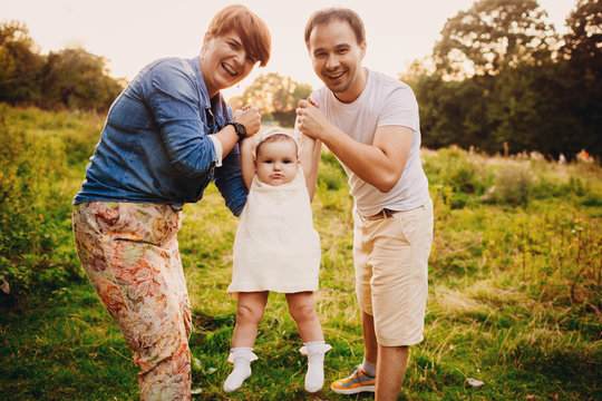 Happy parents hold little girl in white dress