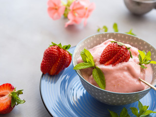 Home made strawberry ice cream in bowl with min leaves