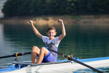 A Young single scull rowing competitor paddles on the tranquil lake