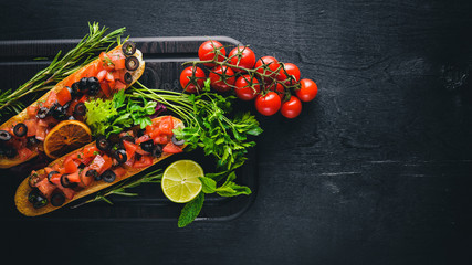 Bruschetta with tomatoes, olives, herbs and parmesan cheese on bread. Cold snacks. Italian cuisine. On Wooden background.