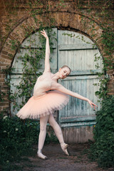 Fototapeta na wymiar Young woman with perfect body in white tutu dancing outdoors with urban background. Beautiful ballerina showing classic ballet poses and jumping high into the air