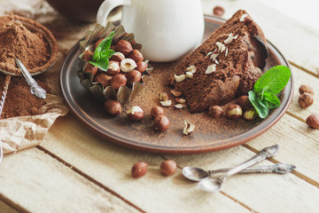 Piece of chocolate cake, mint leaves, hazelnuts and jar with milk