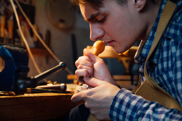 Master artisan luthier working on the creation of a violin. painstaking detailed work on wood.