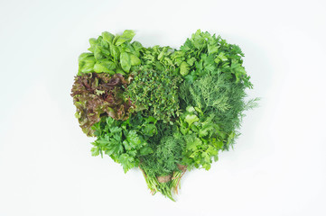 Obraz premium A bouquet of fresh herbs on a white background in the shape of a heart. Healthy eating.