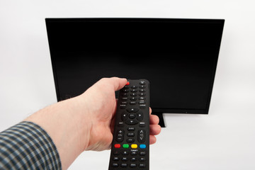 Man's hand using remote control in front of the TV.