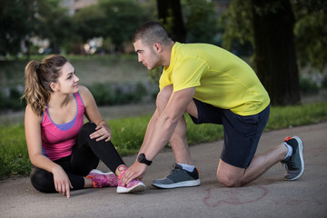 Man helps to woman with injured knee at sport activity