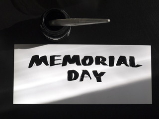 Memorial day calligraphy and lettering post card with inkstand. Top view and sunlight shadow.