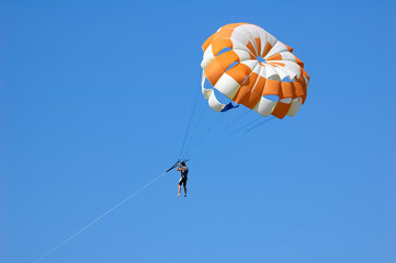 Happy man flying parasailing in a blue sky