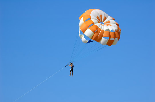 Happy man flying parasailing in a blue sky