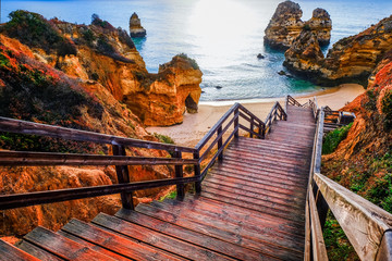 beautiful Atlantic ocean view horizon with sandy beach,  rocks and waves at sunrise. Algarve,  Portugal © ver0nicka