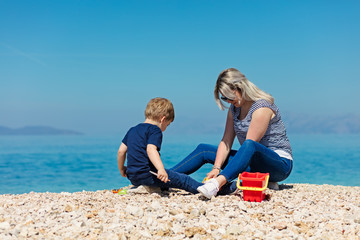 A happy mother and young child boy son having fun on a sunny beach