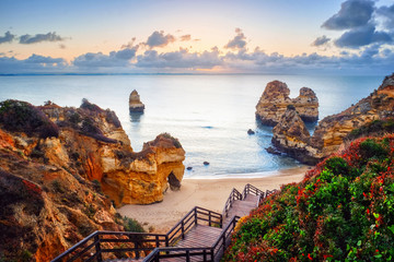 beautiful Atlantic ocean view horizon with sandy beach,  rocks and waves at sunrise. Algarve, ...