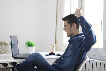 young man with the laptop in the room celebrating euphoric