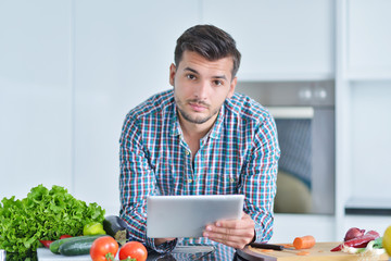 Happy man using digital tablet in kitchen at home