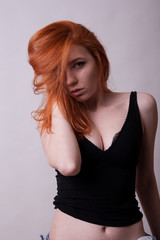 Sensual busty hot redhead woman in studio photo on gray background. Sexuality and sensuality. Attractive model