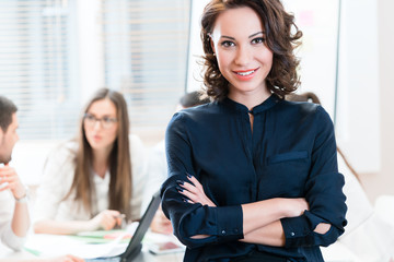 Manager with her team working in the office looking into camera
