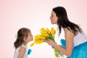 Mom and daughter enjoying the fragrance of flowers.