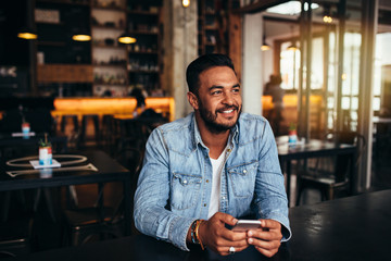 Young man sitting in coffee shop with mobile phone