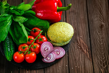 From above shot of process of making hamburger with vegetables, buns and raw meat on board.