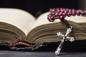Rosary and  cross  on the Bible on a wooden background. Holy book.