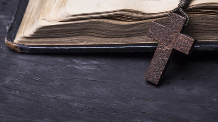 Rosary and  cross  on the Bible on a wooden background. Holy book.