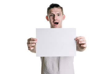 Young handsome guy with a blank sheet of paper, looking surprised at the frame. Place for signature, text. Horizontal frame