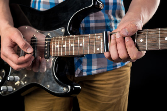 Music and art. Electric guitar in the hands of a guitarist, on a black isolated background. Playing guitar. Horizontal frame