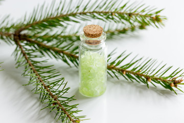 spa with organic spruce sea salt in glass bottles on white table background