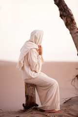 Jesus Christ sitting on a tree stump overlooking sand dunes at sunset, St. Anthony, Idaho