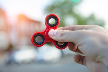 Man playing with fidget spinner stress relieving toy outdoors on city street. - obrazy, fototapety, plakaty