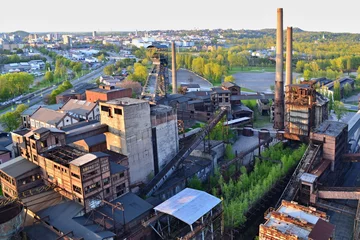 Photo sur Plexiglas Vieux bâtiments abandonnés Usine de ferronnerie abandonnée avec arbres et ville en arrière-plan