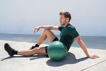 Fit athlete man relaxing at fitness gym during medicine ball workout. Healthy and active lifestyle...