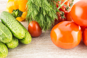 Cucumber, tomato, pepper and fennel on a white wooden background close up.