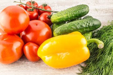 Cucumber, tomato, pepper and fennel on a white wooden background close up.