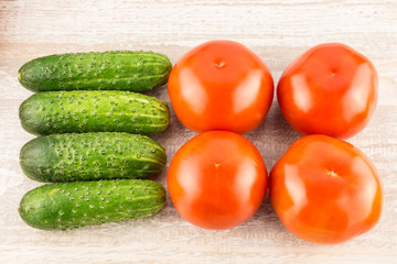 Tomatoes and cucumber on light natural wooden background.