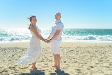 Young romantic couple standing on the beach holding hands