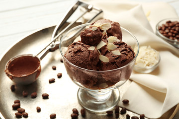 Delicious chocolate ice cream with nut flakes in glass bowl on tray