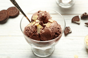 Delicious chocolate ice cream in glass bowl on wooden table