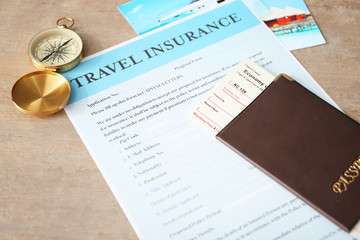 Passport with ticket and compass on travel insurance form