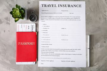 Passport with ticket and pen near blank travel insurance form on grey background