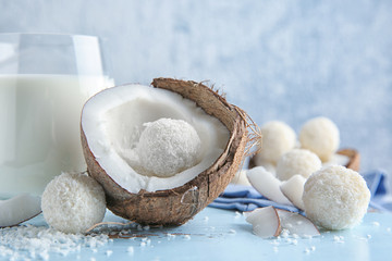 Tasty candies in coconut flakes and fresh nut on wooden board