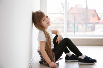 Cute little girl sitting on floor near window. Fashion concept