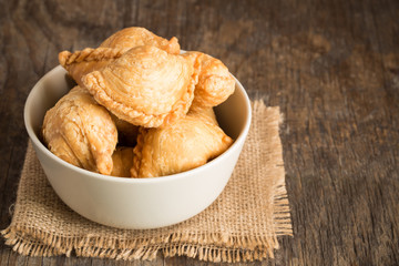 Curry puff in bowl on old wooden table