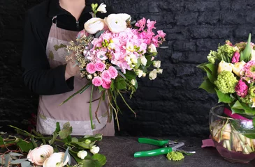 Cercles muraux Fleuriste Fleuriste féminine créant un beau bouquet dans un magasin de fleurs sur fond de mur de briques noires